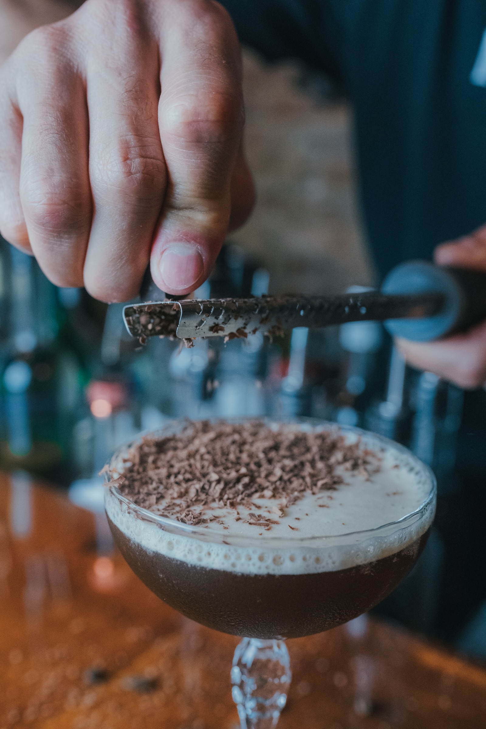 A bartender grating chocolate over an espresso martini